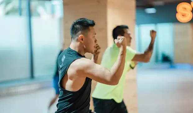 Men performing upper-body strikes during a BODYCOMBAT session at GymNation, focused on cardio and strength.