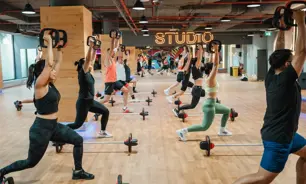 GNمجموعة من الأشخاص يؤدون تمارين ليس ميلز بودي بامب في جيمنيشن دبي، باستخدام القضبان