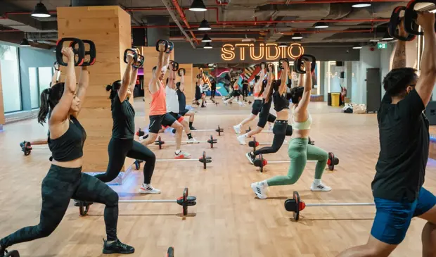 Group of people doing Les Mills BODYPUMP class at GymNation Dubai, using barbells and SMARTBAR equipment